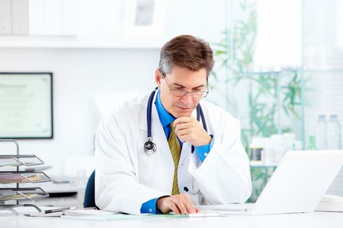 Foto: Arzt sitzt vor Laptop